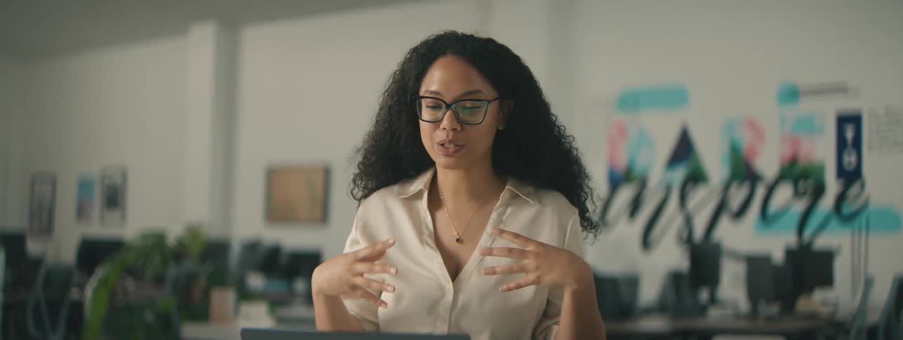 Woman in an office environment talking in front of the laptop
