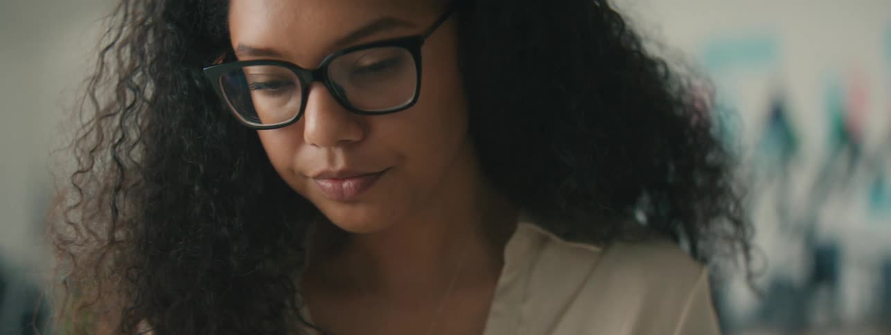 Closeup of the face of a tired young woman with curly hair and glasses