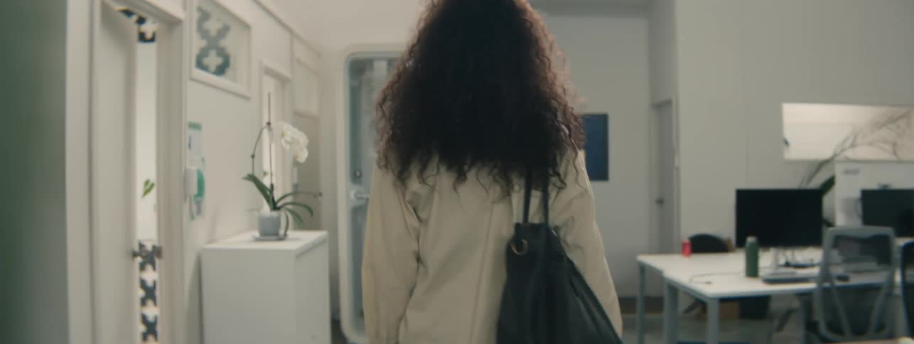 Woman with a bag walking through an office environment