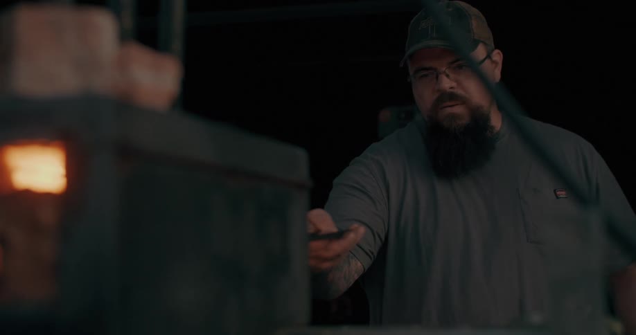 A blacksmith uses a tong to handle hot metal inside a small furnace