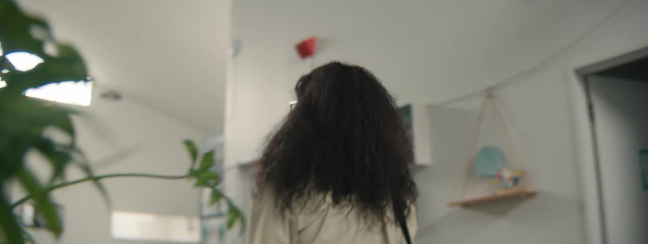 A young woman with curly hair walks through a modern office