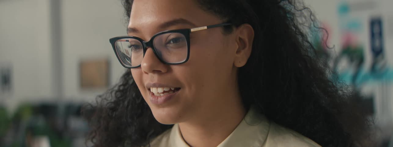 A happy woman with curly hair takes a call on a smartphone in the office