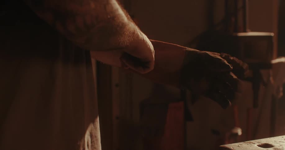 A blacksmith puts on a glove