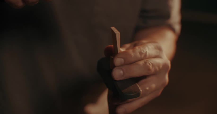 Close up of a mans hands hammering a piece of wood
