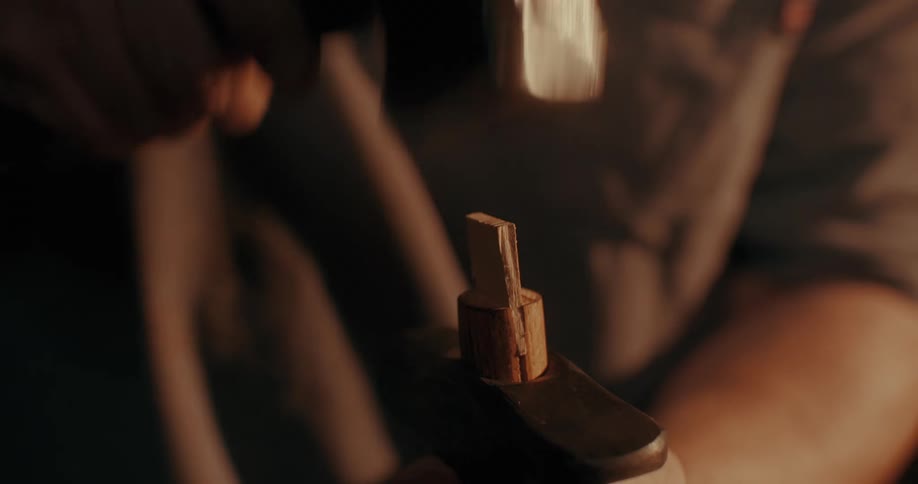 Carpenters hand hammering a piece of wood