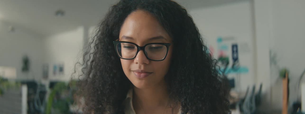 Woman with curly hair and glasses in an office environment