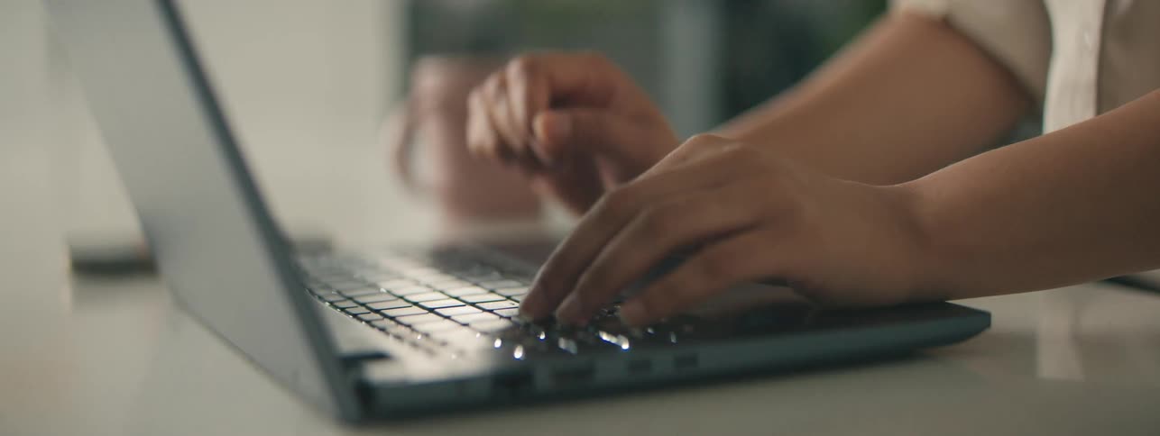 Hands typing on a laptop on the table
