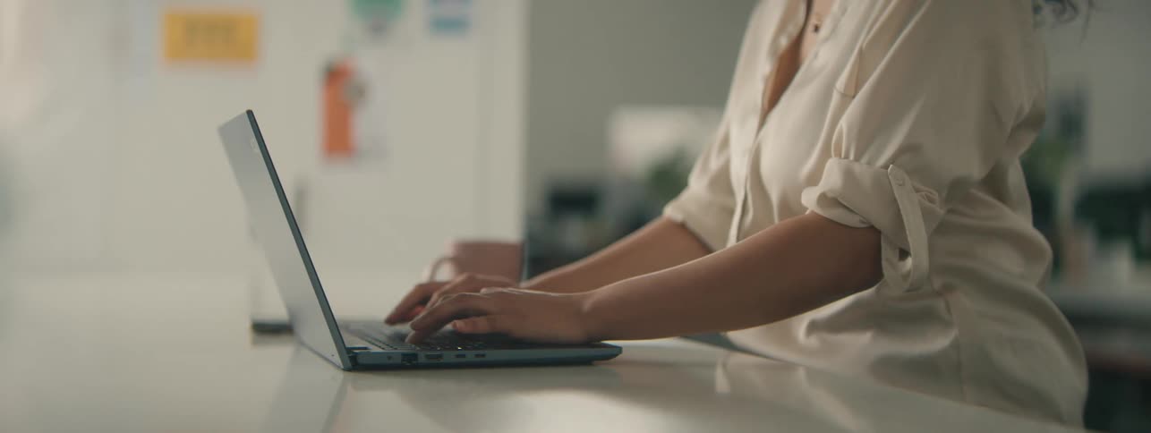 Close up of a person typing on a laptop over a desk