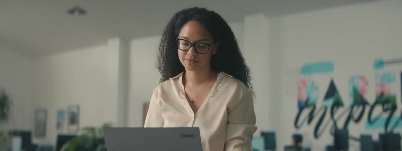 Woman standing in an office environment using a laptop