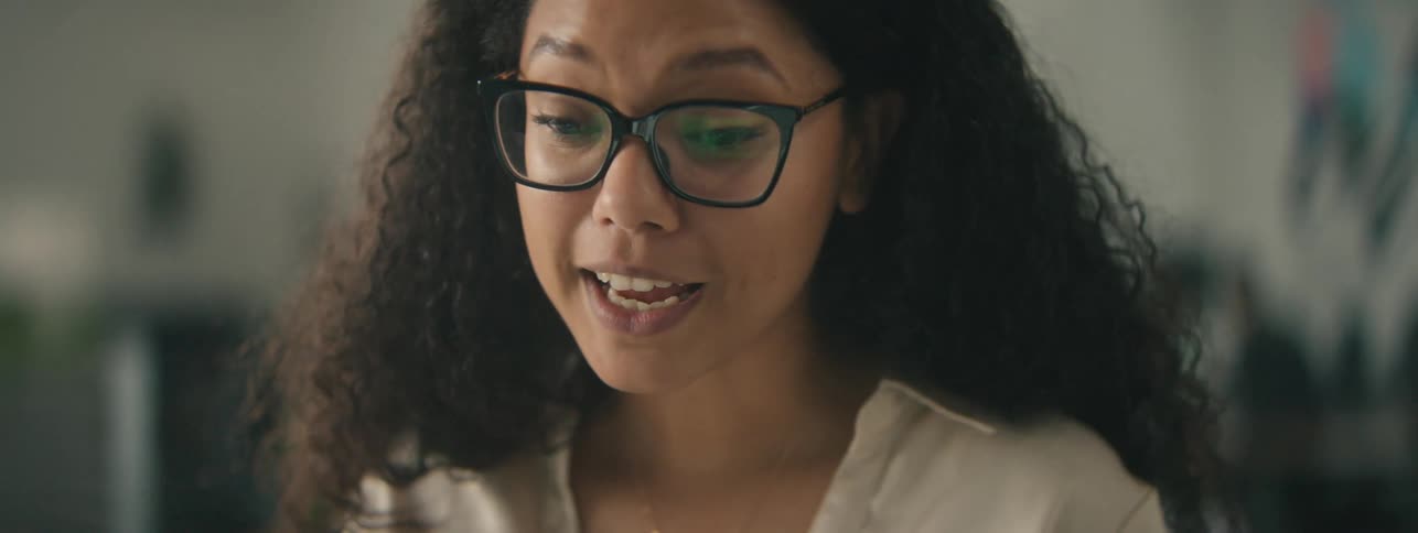 A woman wearing glasses is talking and smiling