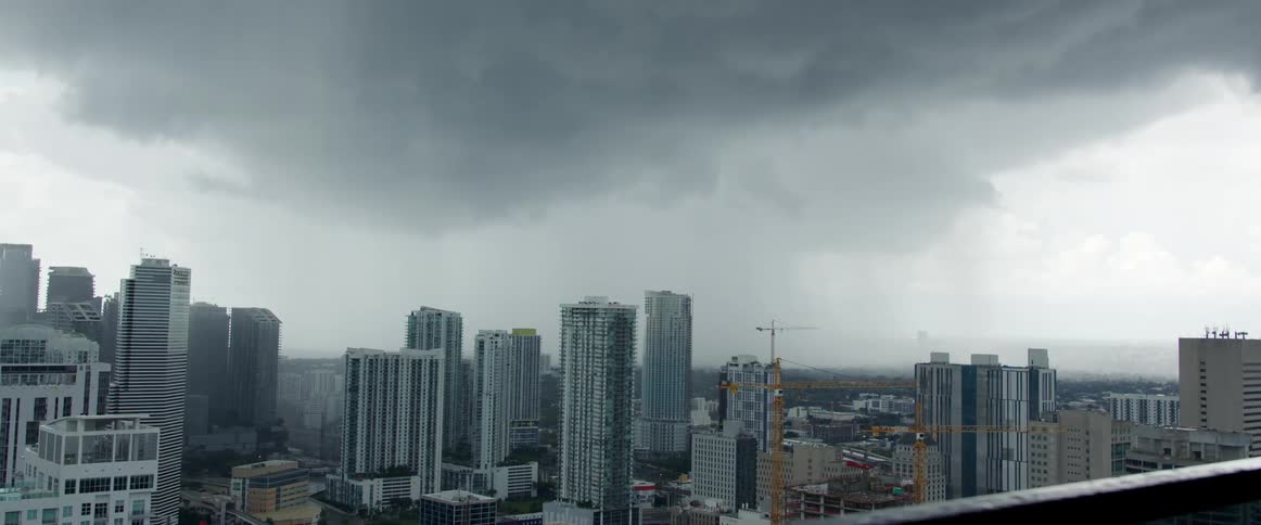 A dark storm cloud looms over a city skyline