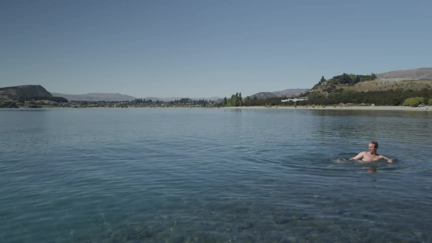 Man swimming in a lake on a sunny day