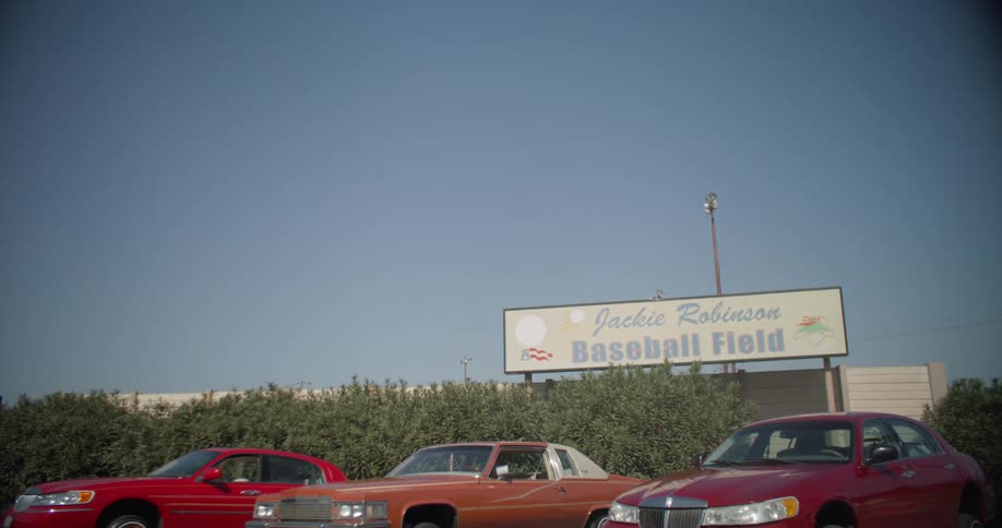 Three lowrider cars parked outside jackie robinson baseball field