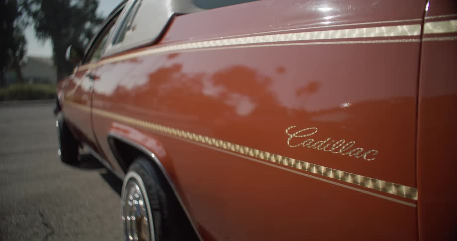 Close up of back end of a vintage brown cadillac parked in a parking lot
