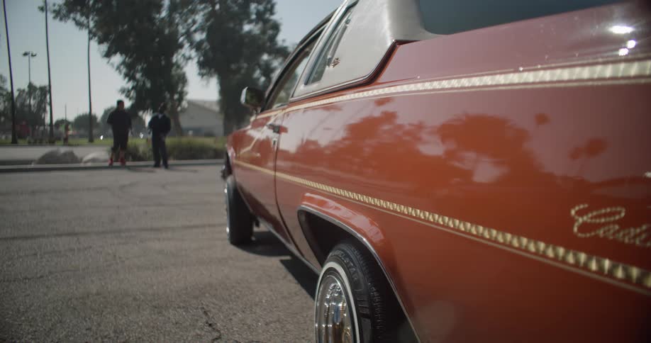 Side view of a red vintage car and two people in the background