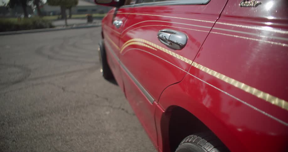 The side of a red car with gold rims and pinstriping