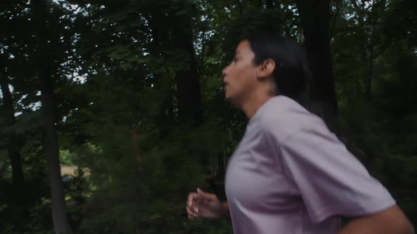 A woman jogging on an empty street surrounded by trees on the neighborhood