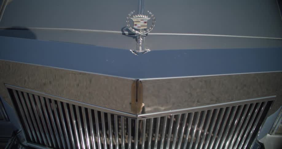 A closeup of a classic cadillac cars chrome grille and hood emblem