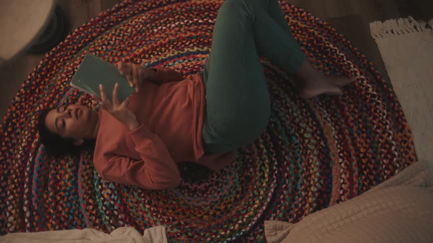 Woman lying on the carpet holding a notebook and a pen