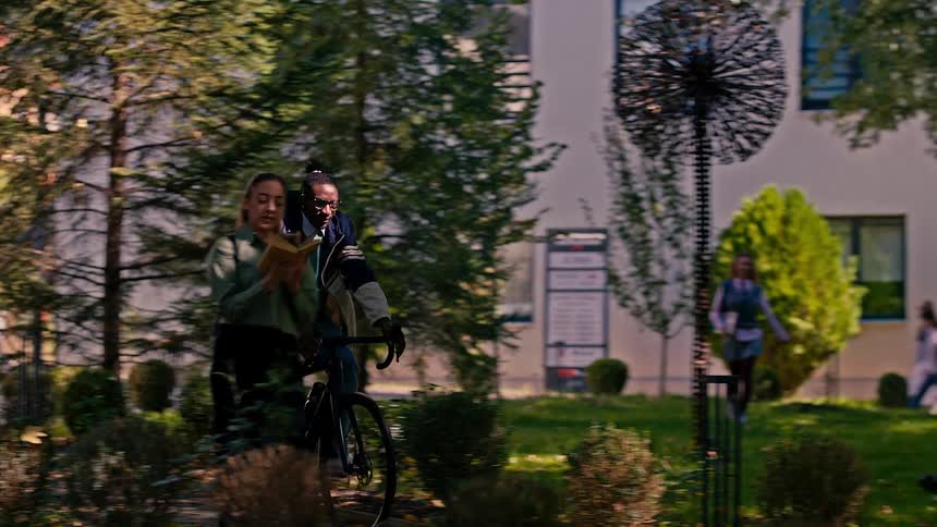 Woman walking reading a book and a man passing by on a bicycle