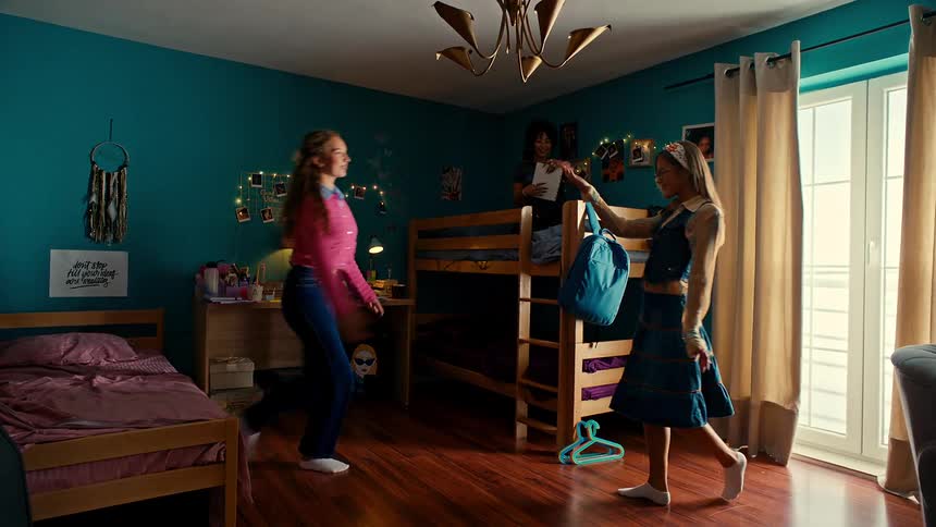 Two teenage girls dance together on a wood floor in a bedroom