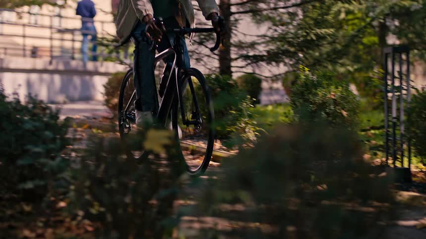 A black man rides a bike through a park
