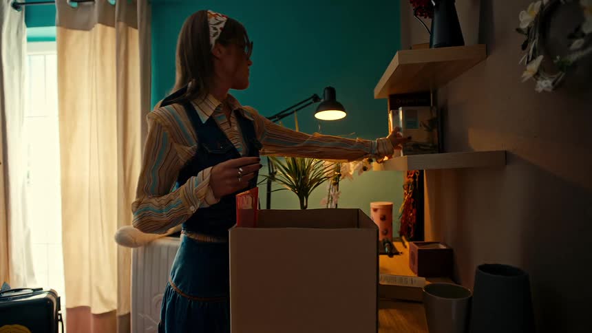 Woman sitting on the toilet taking a selfie and outside in the room with a woman putting books on a bookshelf