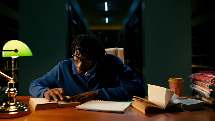 Student sitting at a table late at night in a library