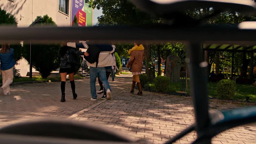 A young man chains a bicycle to a railing and then walks away with his friends