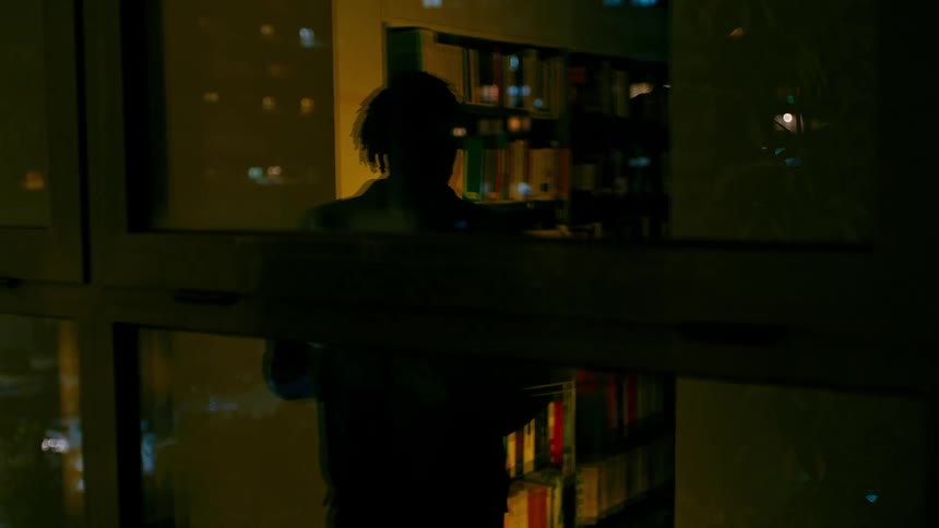 Man walking through a library late at night