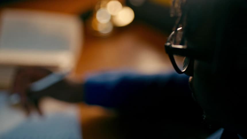 Man leafing through a book and studying late at night