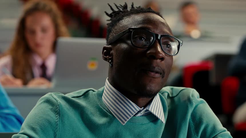 A college student listens to a class and takes notes in the classroom