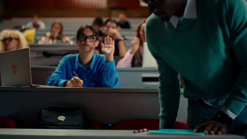 Students in class with one of them arriving late and raising his hands