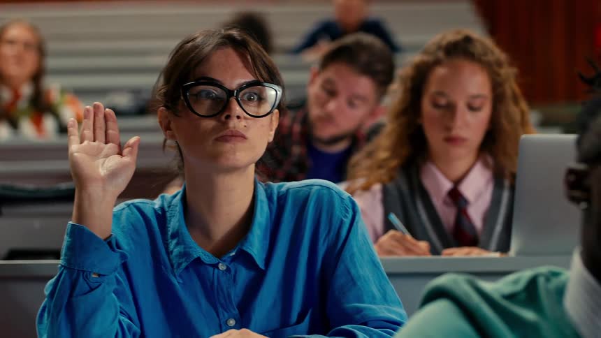 Woman raising her hand while standing in classroom with other students