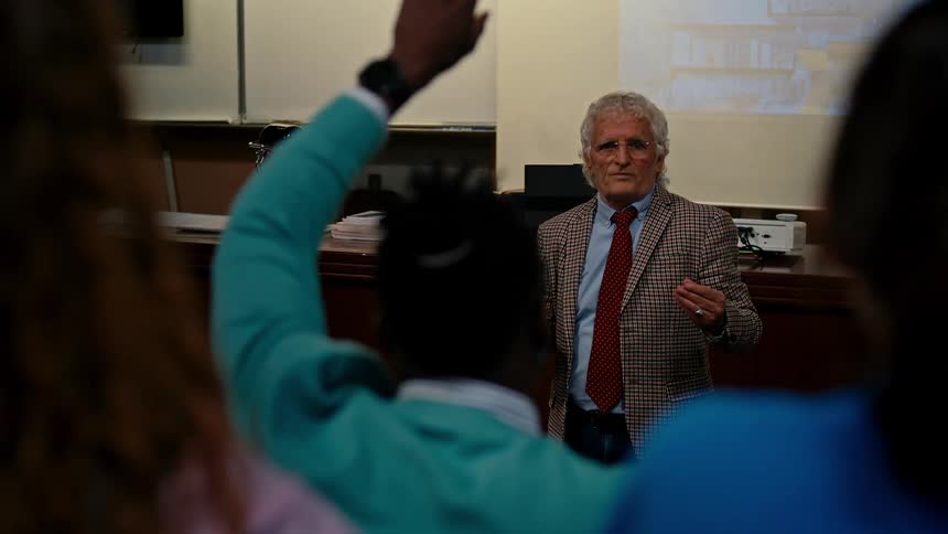 Teacher teaching a class and students raising their hands