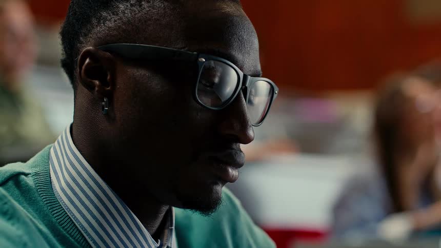 Male student with glasses sitting in classroom concentrating