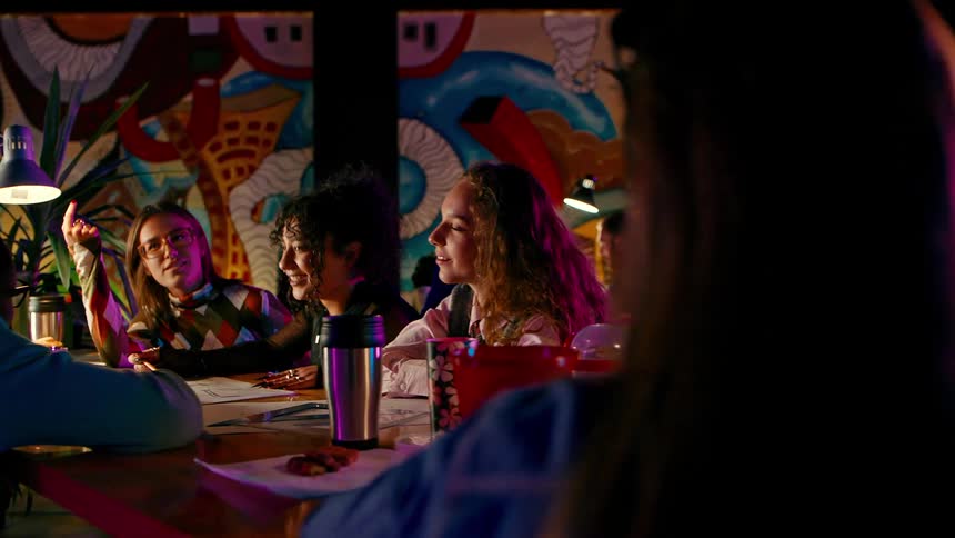Group of friends sitting at a table talking and studying