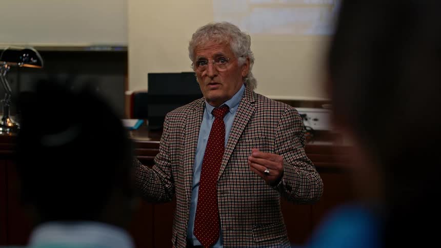 A professor with a pointer teaches and asks for a student to speak to him