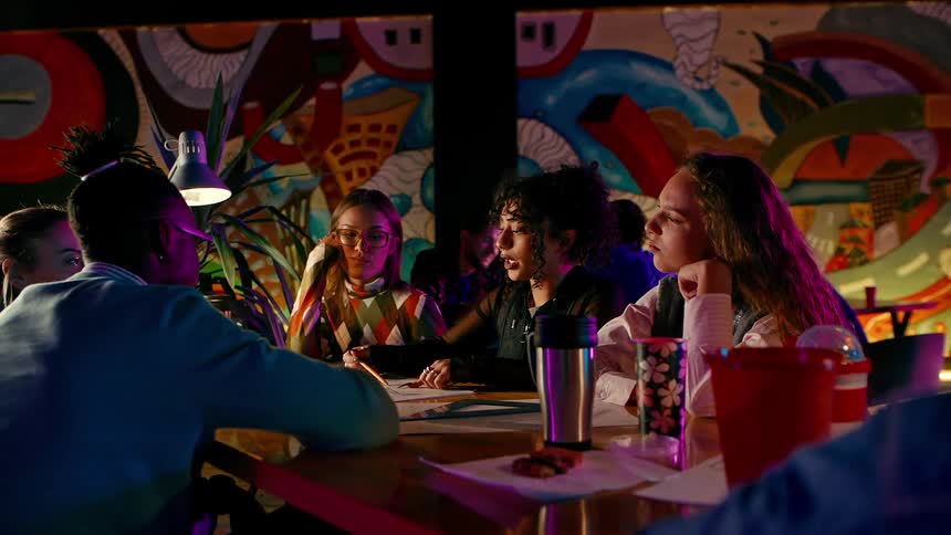 University students work together while sitting in a restaurant decorated with a large mural