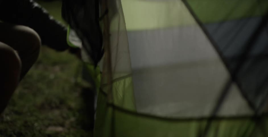 Person unzipping the entrance to their tent and entering
