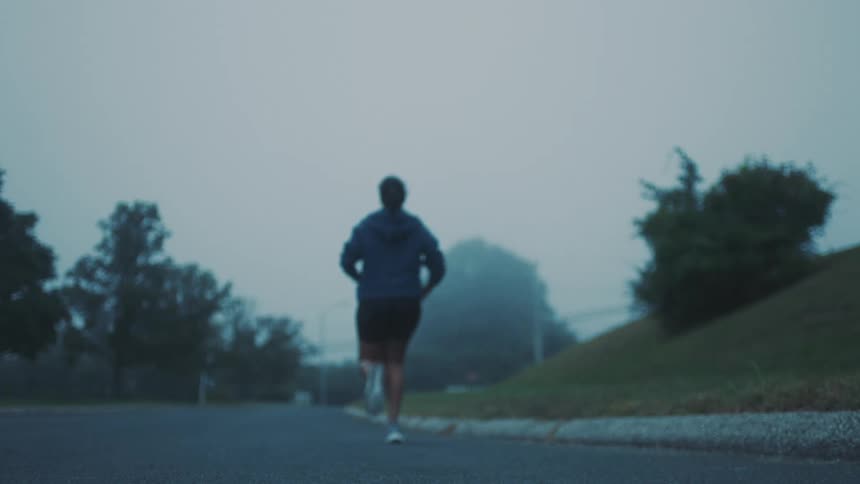 Woman running on a paved treelined street