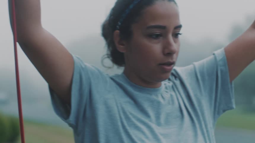 Woman with her arms up and stretching a resistance band