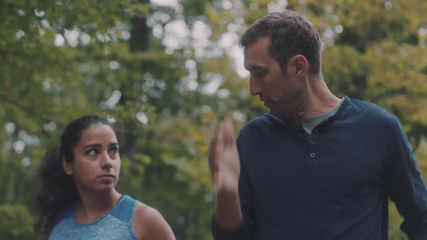 Man making a running arm movement and teaching a woman next to him