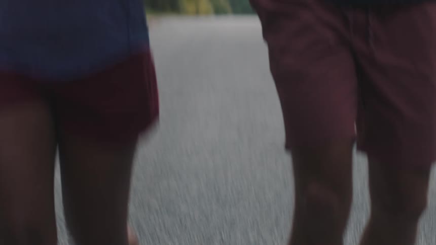 A man and a woman wearing running shoes run down the street