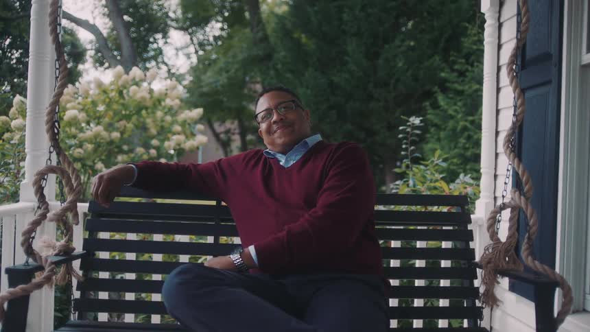 Man sitting on a bench outside a house during the day