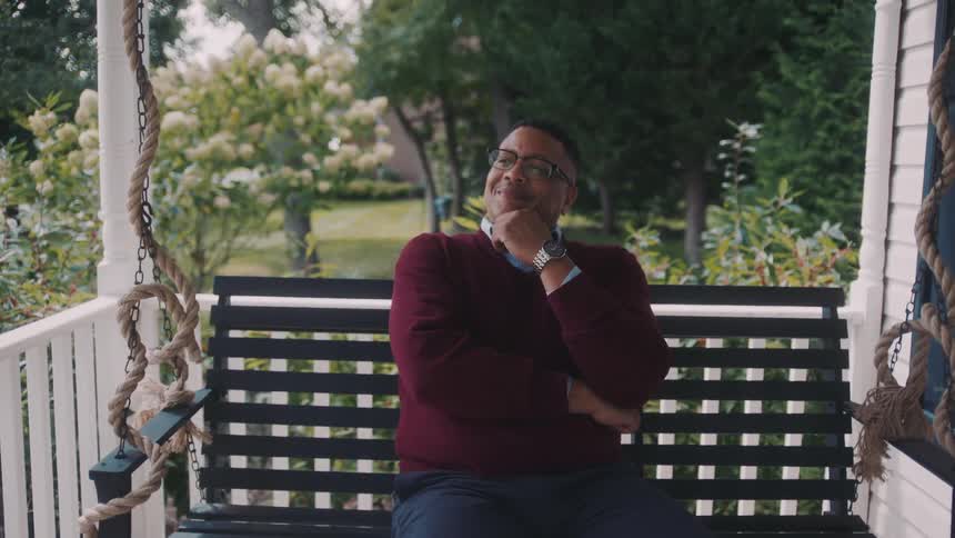 Man sitting on a bench on the porch of a house
