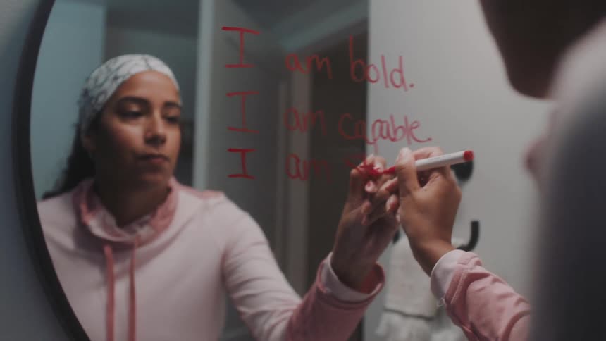 A woman writes a message on a mirror with a red marker