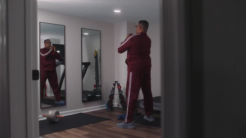 A tall black man performs squats in a home gym