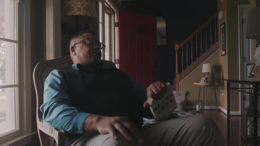 A man dozing off on a chair in the living room checks his wristwatch