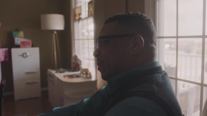 Man sitting in a room of the house next to a window